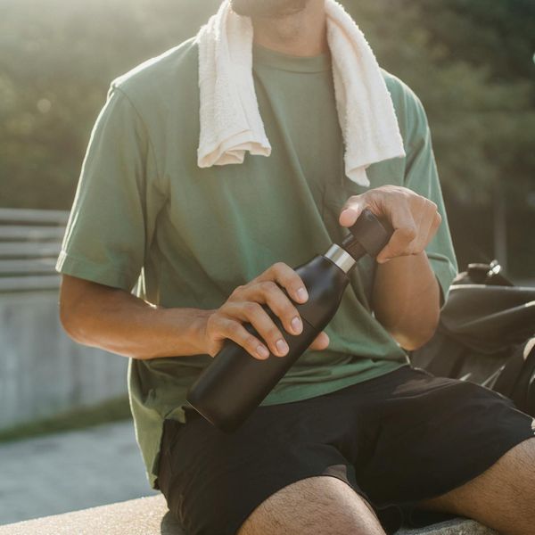 Water bottle and towel on a dark floor.